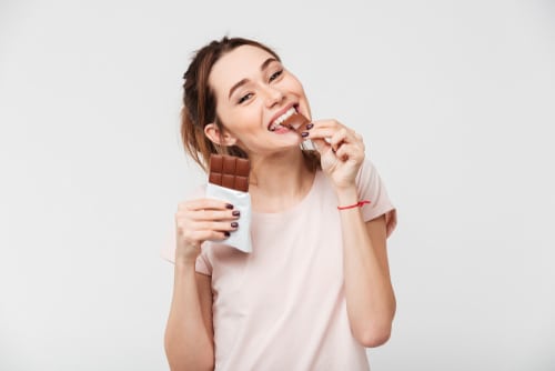 pretty girl biting chocolate bar and looking at camera