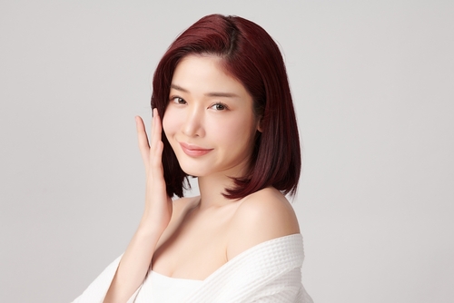 young asian woman with clean fresh skin on grey background