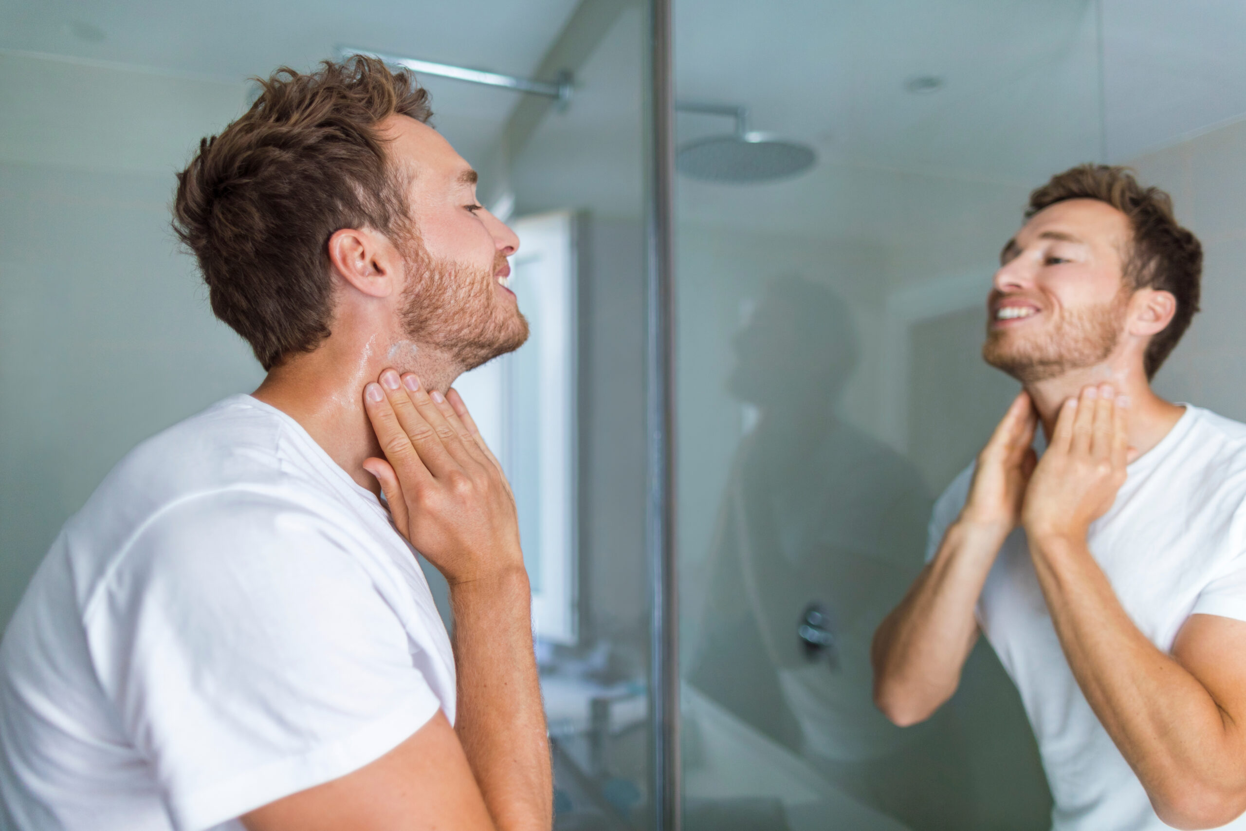 Man washing his face in the mirror to prevent acne breakouts