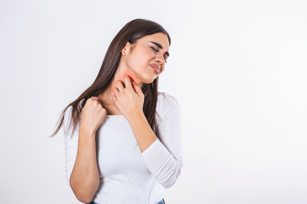 Woman looking uncomfortable, scratching her neck due to winter eczema flare up.