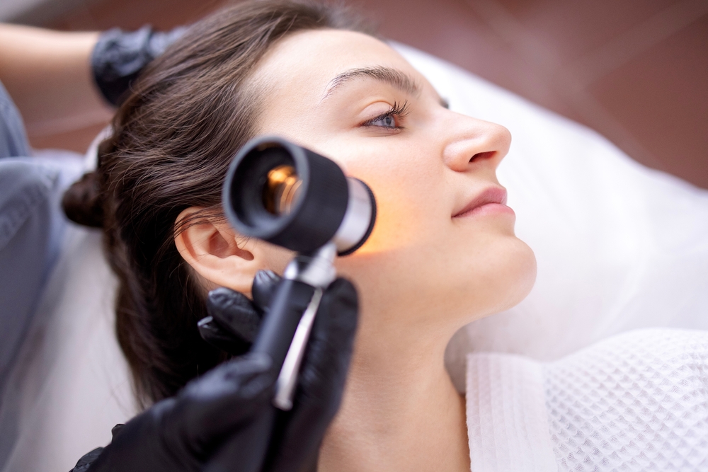 Dermatologist examines a woman’s face for year-end skin check.