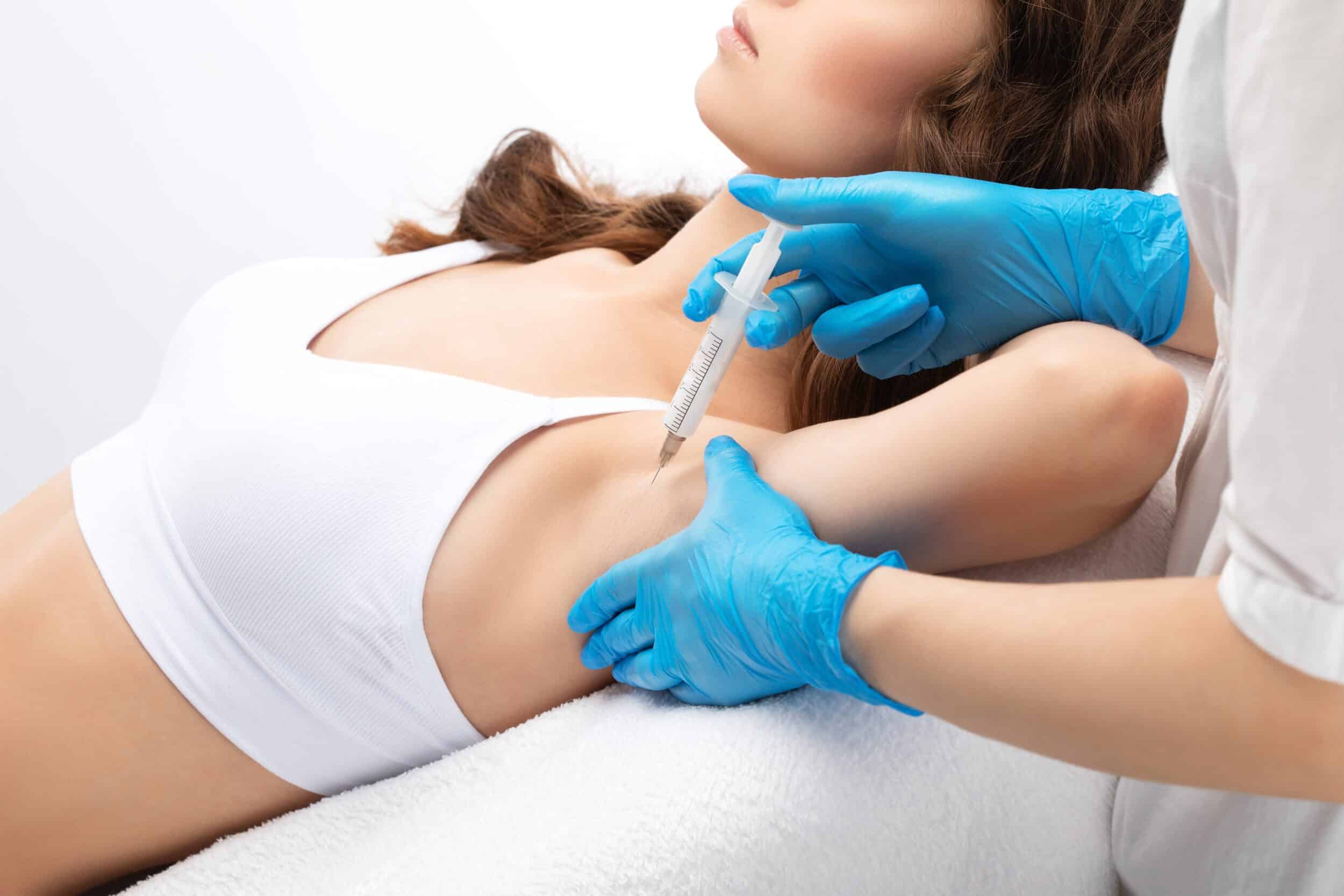 Doctor administering botulinum toxin injections in a woman’s underarm to treat hyperhidrosis in a cosmetic clinic setting