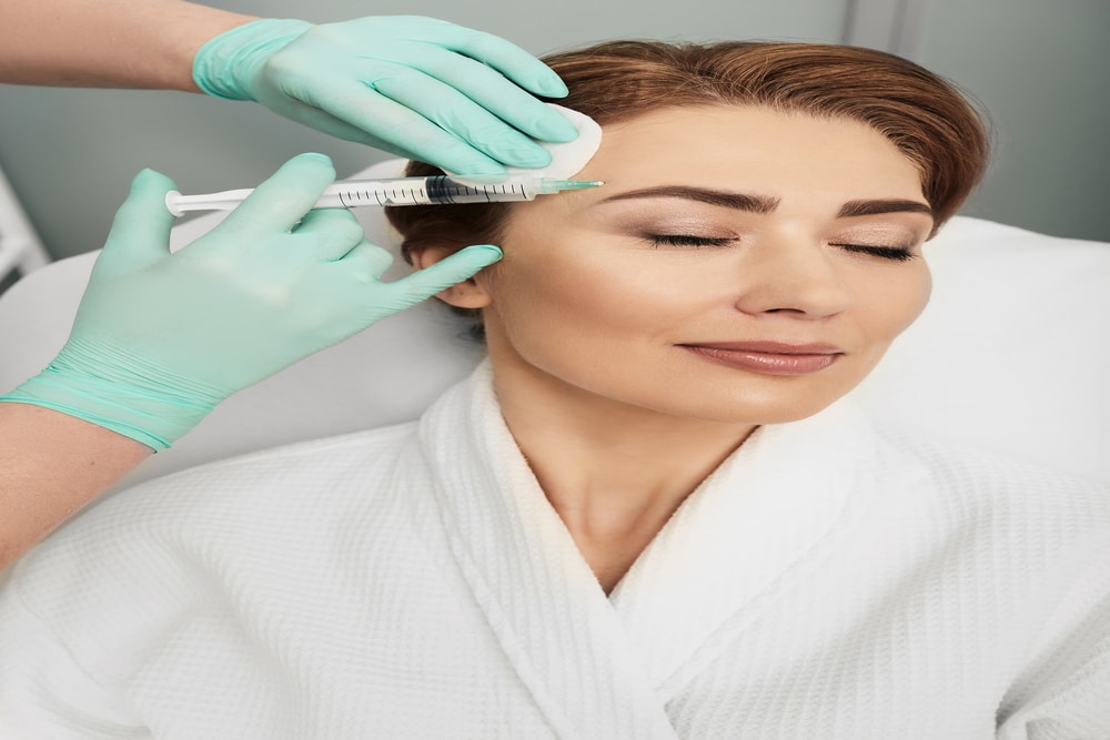 Beautiful woman receiving facial mesotherapy injection from beautician, concept of anti-aging treatment and skin tightening